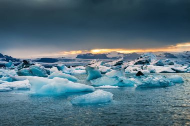 Jokulsarlon Buzul Gölü 'nün güzel manzarası ve mavi buzdağı yaz akşamları İzlanda' daki Vatnajokull Ulusal Parkı 'nda eriyor.