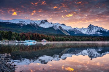 Rocky Dağları 'nın güzel manzarası. Renkli gökyüzü ve feribot teknesi Jasper Ulusal Parkı, Alberta, Kanada' daki Maligne Gölü 'nde demirlemiş.