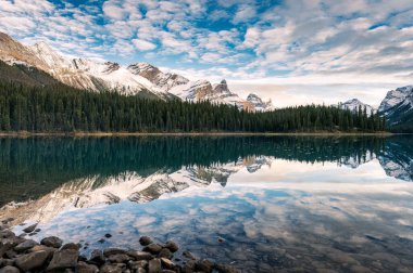 Rocky dağlarının güzel manzarası ve çam ormanı sabahın erken saatlerinde Kanada 'nın Alberta şehrindeki Jasper Ulusal Parkı' nda Maligne Gölü 'ne yansıyor.