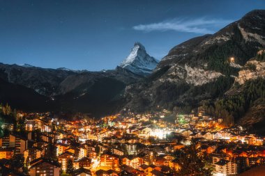 Işık saçan Zermatt köyünün güzel manzarası ve İsviçre 'de gece yıldızlı Matterhorn zirvesi.