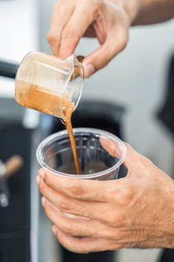 Kahve dükkanında kahve bardağından plastik bardağa kahve dolduran barista.