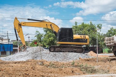 Kazıcı ya da kepçe kepçesi toprağı hareket ettiriyor ve inşaat alanında toprak ve taş kazıyor