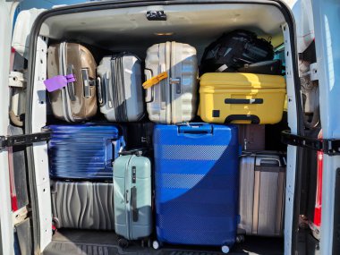 Aile tatili ve özel turizm için hazırlanan valiz ve sırt çantalarıyla dolu büyük bir minibüsün arkasında.