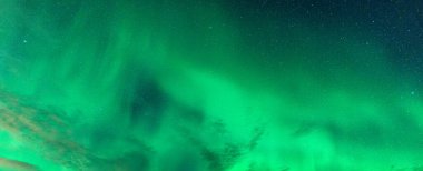 Aurora Borealis 'in sihirli yeşil rengi, Kuzey ışıkları Kuzey Kutup Dairesi' ndeki gece gökyüzünde yıldızlarla parlıyor ve dans ediyor.