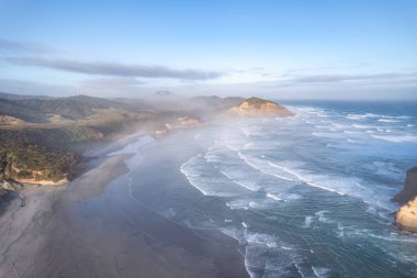 Aerial view of Picturesque sunrise shining over Wharariki beach and archway islands on Tasman sea at West of cape farewell, New Zealand