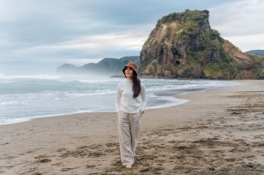 Mutlu genç Asyalı kadın Auckland, Yeni Zelanda 'nın batısında Lion Rock' la Piha Plajı 'nda eğleniyor.