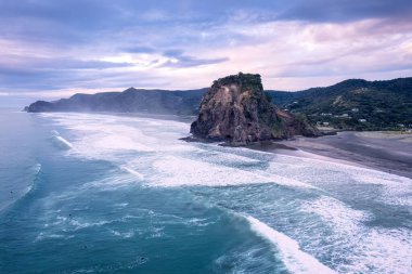 Auckland, Yeni Zelanda 'nın batı kıyısındaki Piha sahilinde güzel ikonik Aslan Kayası ve kırılan dalgaların hava manzarası.