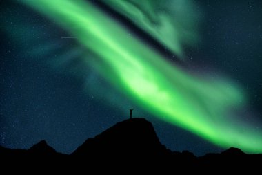 Güzel Aurora borealis. Yıldızlı, siluet yürüyüşçüsü üzerinde parlıyor. Kuzey Kutup Dairesi 'ndeki gece gökyüzünde zirvede duruyor.