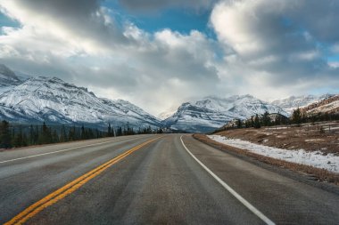 Kanada 'nın Alberta kentindeki Kootenay düzlüklerinde kışın kayalık dağlarla otoyol gezisi.