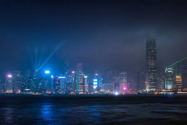 stock image Beautiful night scene cityscape of colorful illuminated business skyscraper building with laser lighting show on Victoria Harbour in foggy day at Hong Kong island 