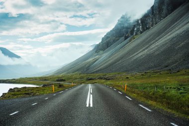 İzlanda 'da sisli engebeli volkanik dağlarla asfalt yolu keşfi