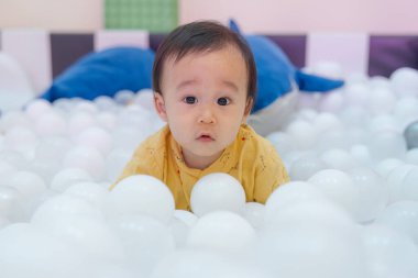 Neşeli, mutlu bir çocuk oyun bahçesinde beyaz topla oynuyor.