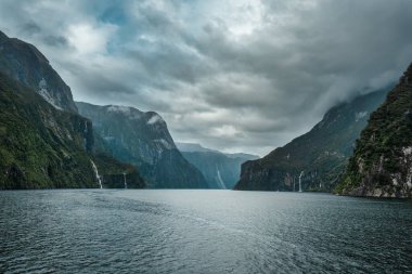 Milford Sound, Fiordland Ulusal Parkı, Yeni Zelanda 'da görkemli bir dağ ve şelale ile seyahat edin.