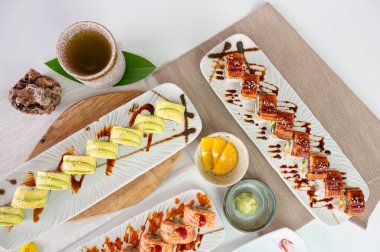 En iyi seramik tepsi, çeşitli somon suşisi, sebzeler, avokado rulosu, ızgara yılan balığı unagi, Japon restoranında iştah açıcı yemek.