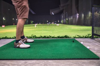 Golf sahasında golf sahasında golf oynayıp pratik yapan bir adam.