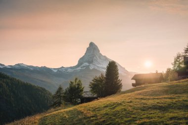 Beautiful golden sunset over Matterhorn mountain with wooden chalet on hill in rural scene at Findeln, Zermatt, Switzerland clipart