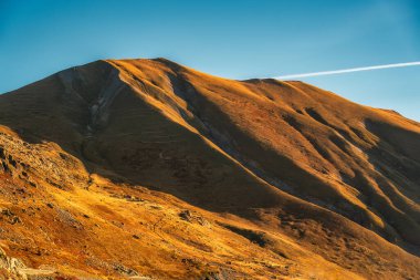 Fransız Alpleri 'nin kırsal kesiminde, kahverengi çimlerle kaplı Rocky dağı ve güneş ışığı parlıyor.