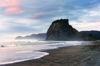 Yeni Zelanda, Auckland 'ın batısında kasvetli bir günde Piha Sahili' ndeki ikonik Aslan Kayası dağının manzarası.