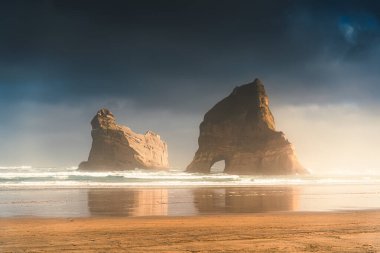 Tazman Denizi 'ndeki Archway adalarıyla dolu Whariki sahilinin dramatik manzarası. Sabah Yeni Zelanda' nın Güney Adası 'nda Cape Farewell' in batısında.
