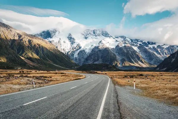 Yeni Zelanda 'nın güney adasında güneşli bir günde asfalt yolda, sonbahar vahşi doğası arasında karla kaplı olarak Cook Dağı' na doğru yol alıyoruz.