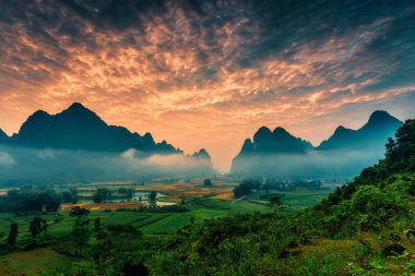 Vietnam 'ın Cao Bang kasabasında Phong Nam Vadisi' nde sisli, nehir ve geleneksel köyle dolu, canlı gündoğumunun dramatik manzarası.