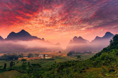 Vietnam 'ın Cao Bang kasabasında Phong Nam Vadisi' nde sisli, nehir ve geleneksel köyle dolu, canlı gündoğumunun dramatik manzarası.