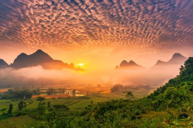 Vietnam 'ın Cao Bang kasabasında Phong Nam Vadisi' nde sisli, nehir ve geleneksel köyle dolu, canlı gündoğumunun dramatik manzarası.