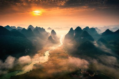 Kırsal köy ve nehrin sisli olduğu dağların üzerinden güzel bir gündoğumu manzarası Phong Nam Vadisi, Cao Bang, Vietnam 'da akıyor.