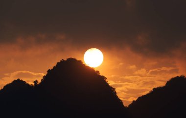 Güzel, canlı bir gün batımı, turuncu gökyüzü siluet dağının tepesinde.