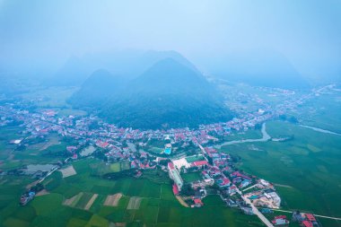 Lang Son, Vietnam 'daki Bac Son Vadisi' nde yemyeşil tarım arazilerindeki banliyö köyü ile sisli bir sabah manzarası.