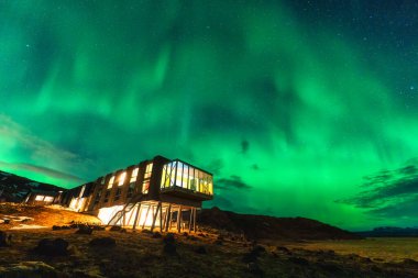 Beautiful scenic view of Aurora borealis, Northern lights glowing over luxury hotel on mount Hengill in winter at Nesjavellir, Iceland clipart