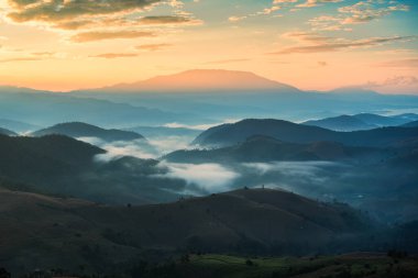 Beautiful rural landscape of golden sunrise shining over Doi Inthanon and foggy mountain on harvest season at Mae Jam, Chiang Mai, Thailand clipart