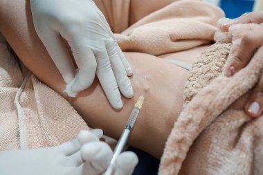 Cilt bakterisi kliniğinde vücut kokusunu ve kırışıklıkları azaltmak için koltukaltına şırınga bakteriyel botulin enjekte eden bir tıp uzmanının yakınlaşması.