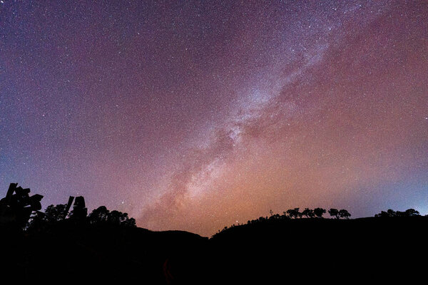 Colorful Milky Way with starry glowing in cosmos galaxy over mountain in remote wilderness