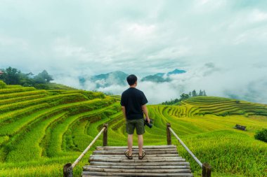 Erkek gezgin, balkonda, Ha Giang, Hoang Su Phi, Vietnam 'daki pirinç tarlalarının arasında duruyor.