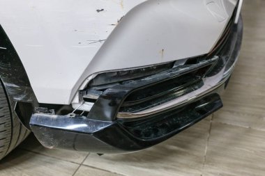 Çağdaş beyaz SUV arabasının önü, garajda park halindeki çarpışma sonucu hasar gördü ve tampon ve vücut parçalandı.