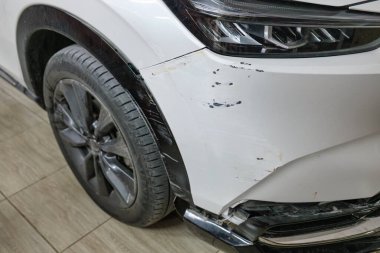Çağdaş beyaz SUV arabasının önü, garajda park halindeki çarpışma sonucu hasar gördü ve tampon ve vücut parçalandı.