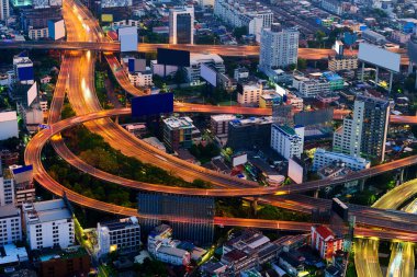 Işıklandırılmış gökdelen binası olan ve şafak vakti otoyol ve reklam panolarında trafiği hızlandıran modern gelecekçi Bangkok şehrinin şehir manzarası 