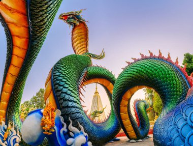 Akşam Wat Phra That Nong Bua, Ubon Ratchathani, Tayland 'da Sri Maha Pho Chedi stupa' yı çevreleyen Gökkuşağı oyma yılanı veya Vibrant Thai Naga
