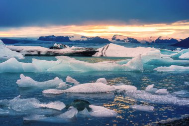 Yazın İzlanda, Vatnajokull Ulusal Parkı 'ndaki Jokulsarlon buzulunda yüzen mavi buzdağının üzerinde gün batımının manzarası