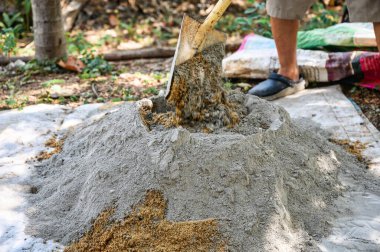 İnşaat işçisi geleneksel bir beton hazırlık yöntemi olan kürek ve mala kullanarak kum, çimento ve suyu elle karıştırıyor.