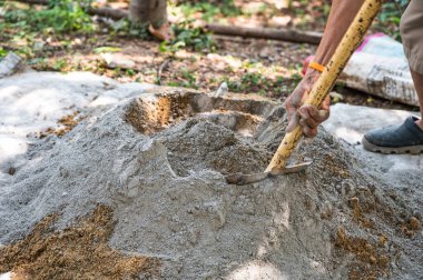 İnşaat işçisi geleneksel bir beton hazırlık yöntemi olan kürek ve mala kullanarak kum, çimento ve suyu elle karıştırıyor.