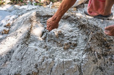 İnşaat işçisi geleneksel bir beton hazırlık yöntemi olan kürek ve mala kullanarak kum, çimento ve suyu elle karıştırıyor.