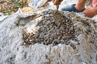 İnşaat işçisi geleneksel bir beton hazırlık yöntemi olan kürek ve mala kullanarak kum, çimento ve suyu elle karıştırıyor.