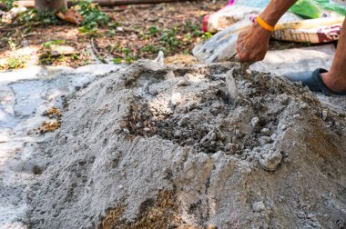 İnşaat işçisi geleneksel bir beton hazırlık yöntemi olan kürek ve mala kullanarak kum, çimento ve suyu elle karıştırıyor.