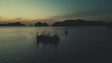 Vietnam 'ın balık tutma geleneğini göz kamaştırıcı hava manzaralarıyla keşfedin. Gün batımına karşı siluetlenmiş, geleneksel tekneler balıkçıların otantik yaşam tarzını ortaya koyuyor.
