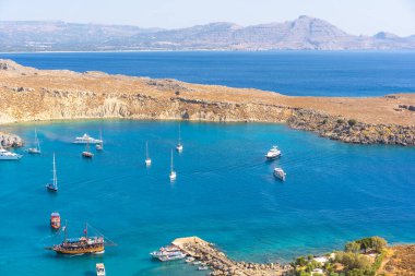 Lindos, Greece - August 2022 : Boats and yachts in the stunningly beautiful Lindos Bay, Rhodes, one of the Dodecanese Islands in the Aegean Sea