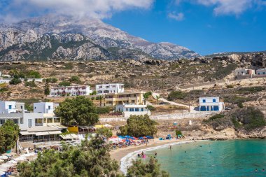 Lefkos Beach, Karpathos, Greece - August 2022 : Hotels and restaurants above the white sandy beach and crystal clear water on a popular and beautiful greek beach