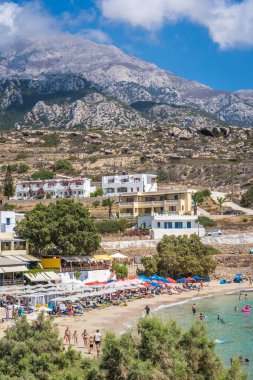 Lefkos Beach, Karpathos, Greece - August 2022 : Hotels and restaurants above the white sandy beach and crystal clear water on a popular and beautiful greek beach