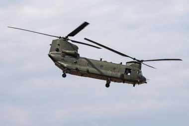 Bulutlu bir gökyüzüne karşı çift pervaneli askeri nakliye helikopteri. Birliklerin nakliyesi, topçu yerleştirilmesi ve savaş alanı ikmal operasyonları için ağır yük uçakları kullanılıyor..